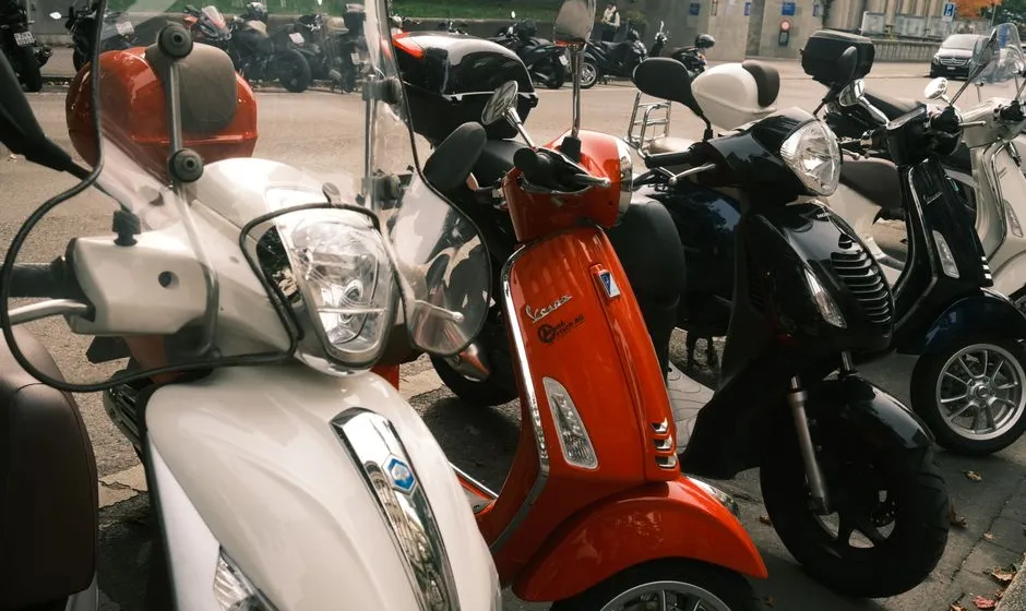Scooter 125 urbain stationné en centre-ville, casque posé sur la selle, lumière douce du matin
